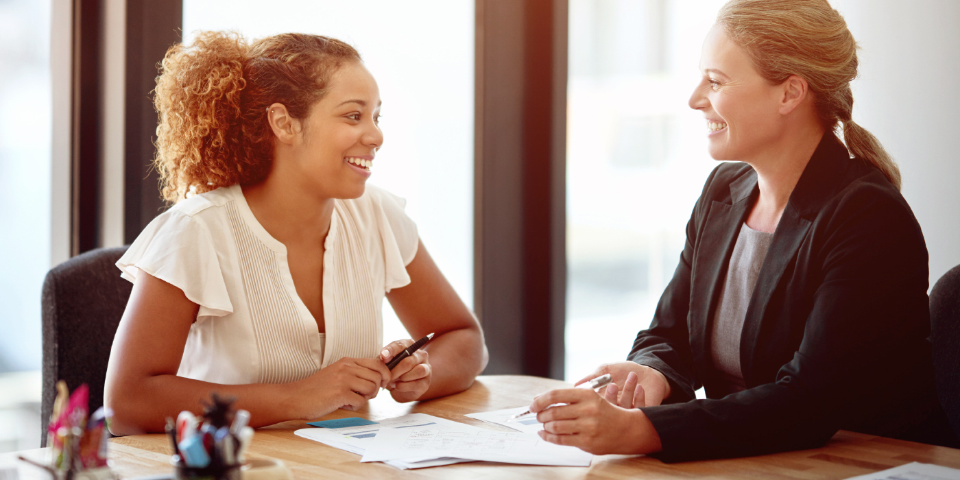 Banner com duas mulheres sentadas à mesa conversando.